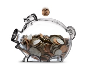 Ethnic female's hand dropping a coin into a half filled clear piggy bank.